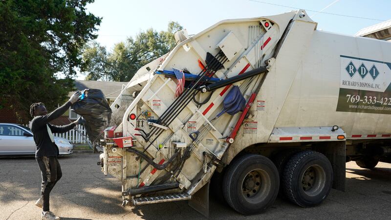 A Richard's Disposal employee places residential garbage into a rear loading trash truck on...