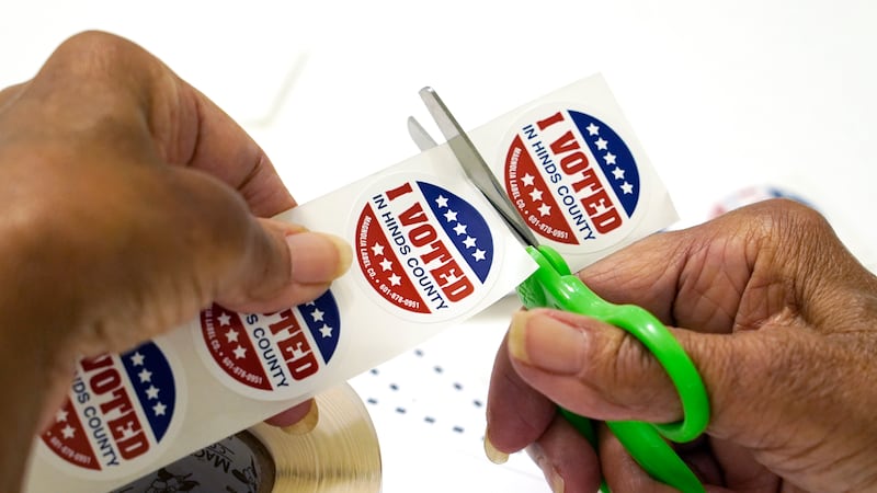 A Jackson, Miss., precinct worker cuts individual "I Voted in Hinds County" stickers from the...