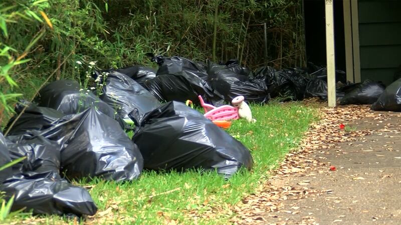 Jackson residents clean up trash after it was dumped in another yard early in the city's trash...