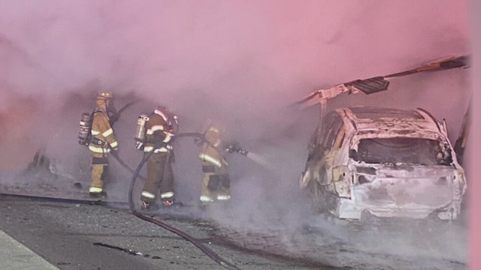 Firefighters in Hancock County work to put out the flames after a tractor-trailer carrying...