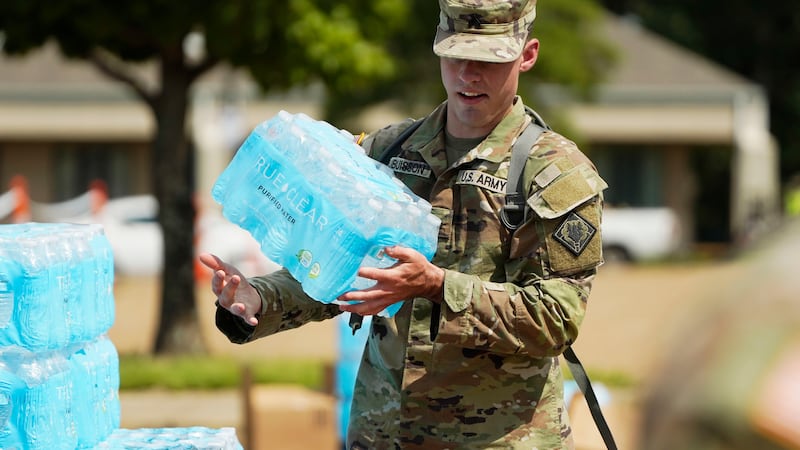 A Mississippi National Guardsman juggles a case of drinking water as he approaches a Jackson,...